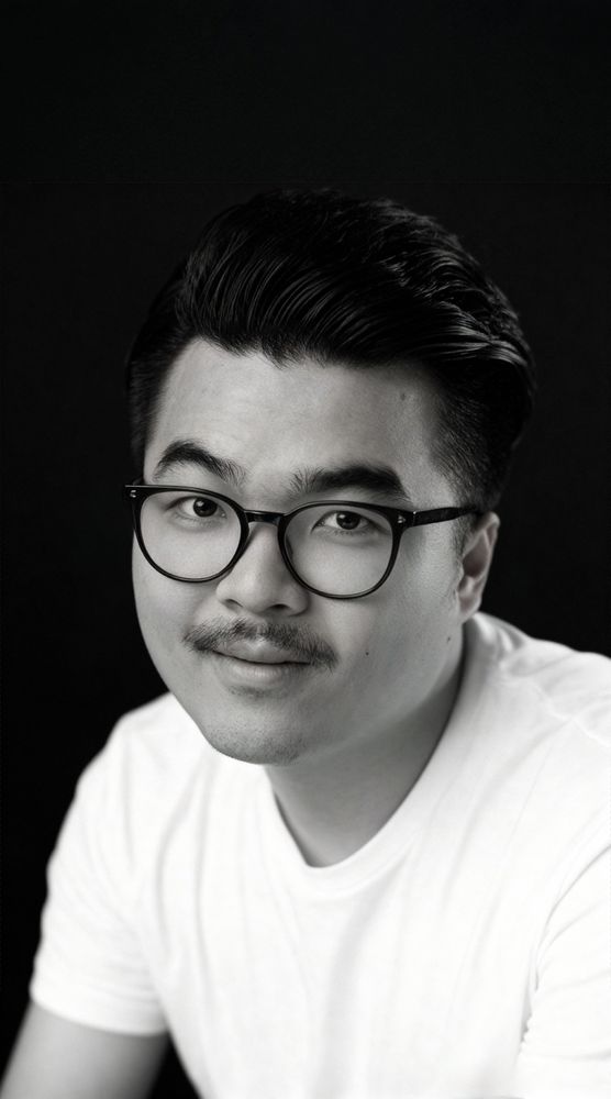 Black and white headshot of Johan Huỳnh in glasses and a white t-shirt