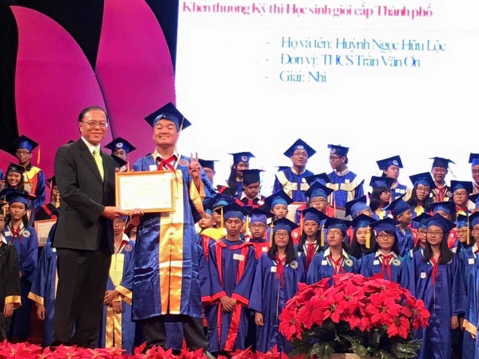 Johan on stage receiving a Ho Chi Minh City history prize certificate at a student award ceremony